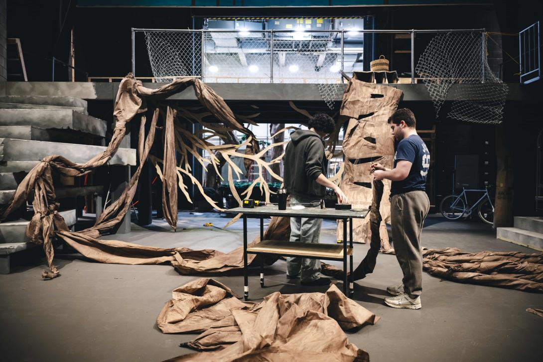 Students construct giant roots that spread across a stage.
